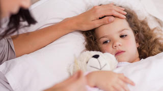 Kind liegt mit Fieber im Bett
