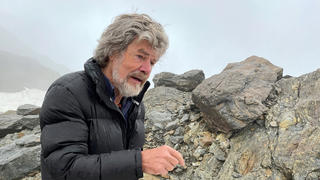 ARCHIV - 15.09.2021, Italien, Tisenjoch: Extrem-Bergsteiger Reinhold Messner bei einem Interview am Fundort der Gletschermumie Ötzi anlässlich des 30. Jahrestags des Funds. Messner (78) sieht wie viele andere Experten angesichts des Klimawandels stei