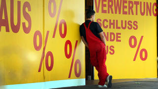 ARCHIV - 26.05.2009, Nordrhein-Westfalen, Düsseldorf: Ein Mann lehnt am Hinweisschild einer Insolvenzverwertung. Die Zahl der Unternehmens- und Verbraucher-Insolvenzen hat in Nordrhein-Westfalen zugenommen. (zu dpa «Mehr Insolvenzen in NRW») Foto: Martin Gerten/dpa +++ dpa-Bildfunk +++