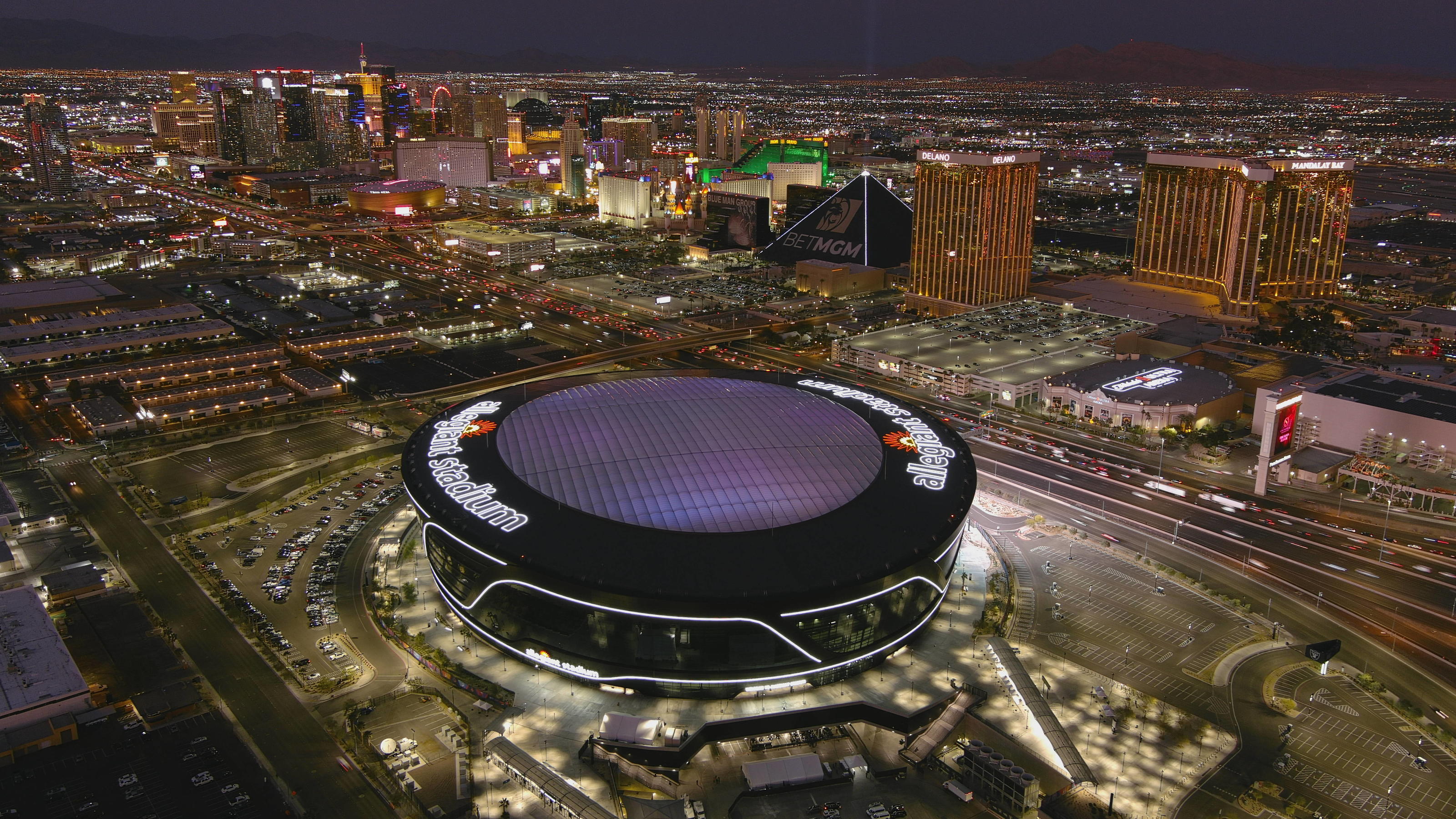 Luftaufnahme des Allegiant Stadiums in Las Vegas am Abend mit dem Strip im Hintergrund