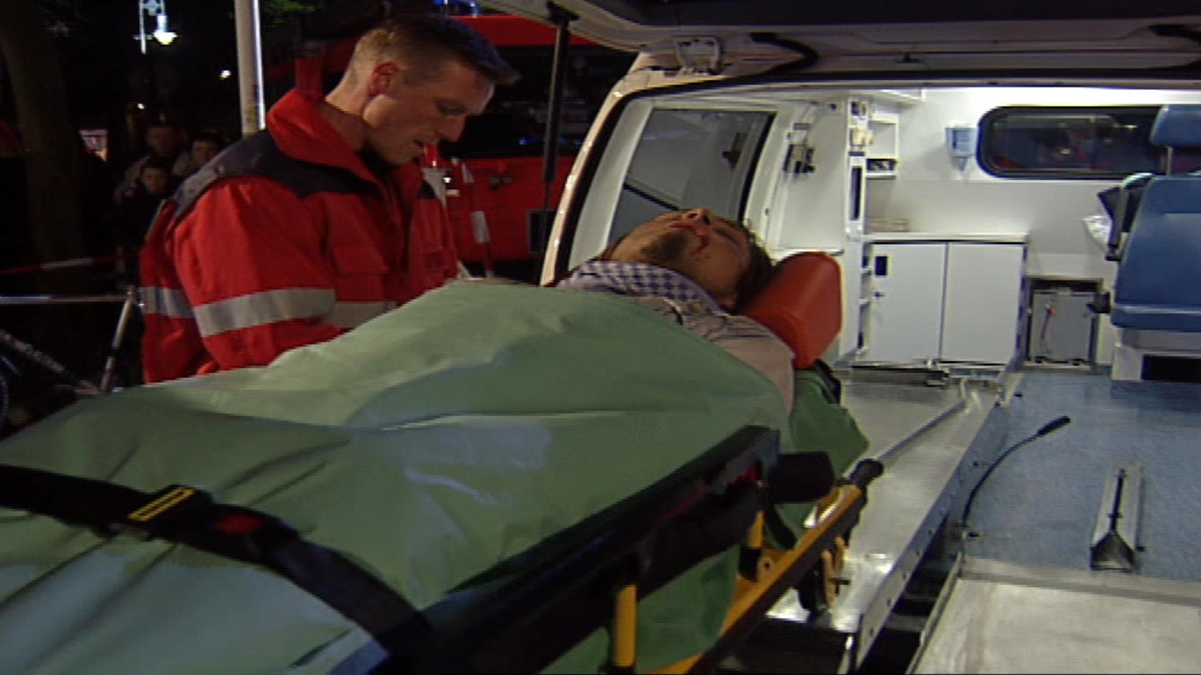 Kai wird auf einer Liege in ein Krankenwagen gebracht.
