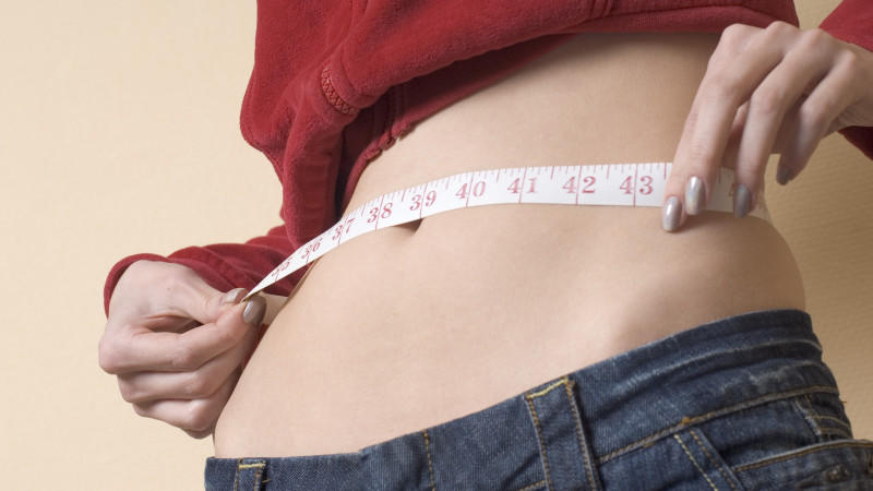 Eine magersüchtige Frau misst ihren Bauchumfang