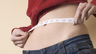young woman measuring her waistline Keine Weitergabe an Drittverwerter., Royalty free: Bei werblicher Verwendung Preis auf Anfrage