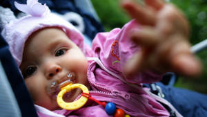 Ein neun Monate altes Baby mit Nuckel liegt im Kinderwagen und versucht zur Kamera des Fotografen zu fassen, aufgenommen am 05.07.2007 im brandenburgischen Sieversdorf (Oder-Spree). Foto: Patrick Pleul  +++(c) dpa - Report+++
