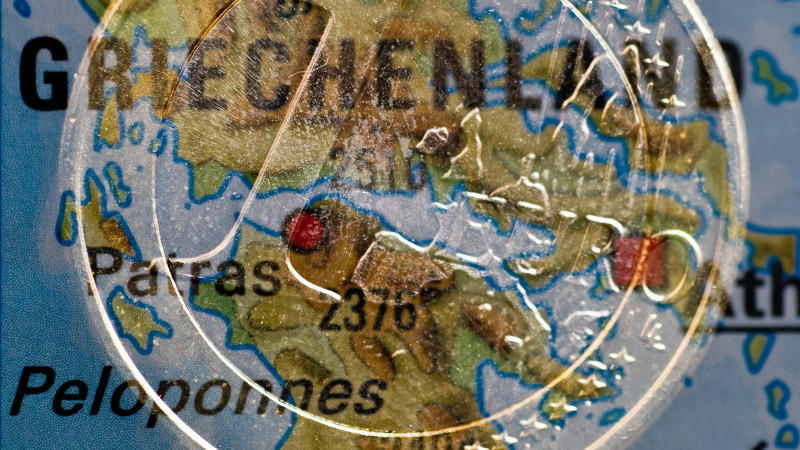 ARCHIV - ILLUSTRATION - Eine Ein-Euro-Münze liegt auf einer Landkarte von Griechenland (Aufnahme mit Doppelbelichtung), aufgenommen am 28.11.2012 in Frankfurt (Oder, Brandenburg). Der Bundestag entscheidet am Freitag (30.11.2012) über die neuen Milliardenhilfen für Griechenland. Foto: Patrick Pleul/dpa  +++(c) dpa - Bildfunk+++