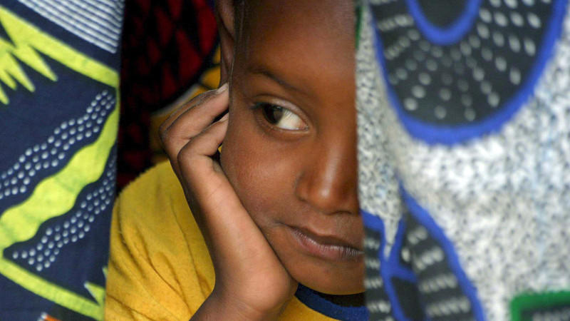 A young Senegalese girl under cover in her mother's traditional clothes, while they attend the official renouncement ceremony of Female Genital Cutting (FGC) at a ceremony in Kidira, eastern Senegal, Sunday 12 March 2006. The town of Kidira on the bo
