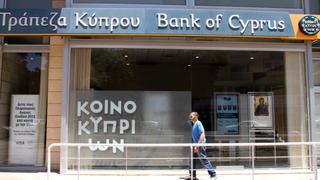 ARCHIV - Ein Mann läuft vor einer Filiale der Bank of Cyprus in Nikosia (Archivfoto vom 27.06.2012). Auf dem EU-Gipfel in Brüssel wird auch über ein Hilfspaket für Zypern beraten.  EPA/KATIA CHRISTODOULOU +++(c) dpa - Bildfunk+++