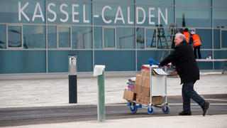 Ein Mann transportiert am 03.04.2013 am Flughafen Kassel-Calden (Hessen) Kisten auf einem Trolley. Nach rund 15 Jahren des Planens, Prüfens und Bauens wird an diesem Donnerstag (04.04.2013) der neue Flughafen Kassel-Calden eröffnet. Foto: Uwe Zucchi/dpa +++(c) dpa - Bildfunk+++