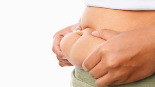 hand pinching fat on tummy for obese concept over white background