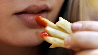 Eine junge Frau isst Pommes Frites mit Ketchup. Foto: MARJA AIRIO +++(c) dpa - Report+++