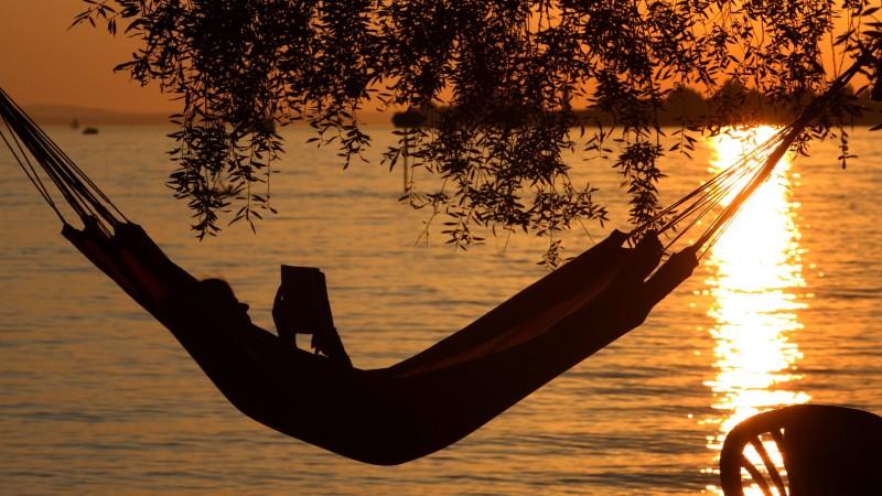 Eine Frau liest am Samstag (20.08.2011) in einer Hängematte am Badestrand eines Campingplatzes in Lindau (Schwaben) ein Buch. Ideales Strand- und Badewetter herrscht derzeit am Bodensee. Die Temperaturen steigen bis auf 32 Grad. Foto: Karl-Josef Hild