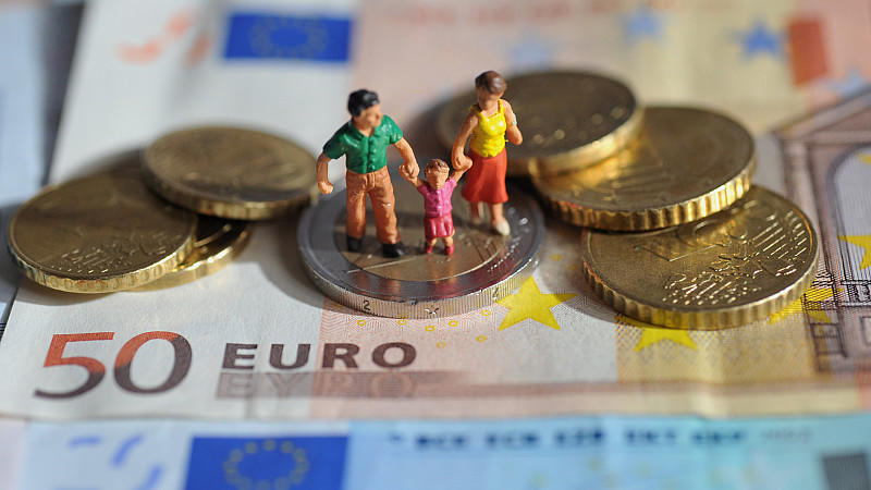 ARCHIV - ILLUSTRATION - Ein Paar mit einem Kind steht auf einer Zwei-Euro-Münze, die auf Geldscheinen liegt, aufgenommen am 16.02.2011. Wegen hoher Mietkosten rutschen einkommensschwache Familien laut einer Studie in vielen größeren deutschen Städten