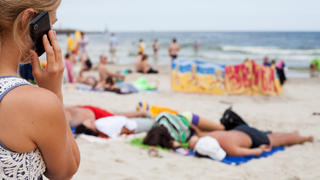 ILLUSTRATION - ARCHIV - Eine Frau telefoniert am 04.08.2013 mit einem Mobiltelefon am Strand von Kolberg, Polen, an der Ostsee. Foto: Daniel Naupold/dpa (zu dpa «EU-Kommission will Roaming-Gebühren schrittweise abschaffen» vom 10.09.2013) +++(c) dpa - Bildfunk+++