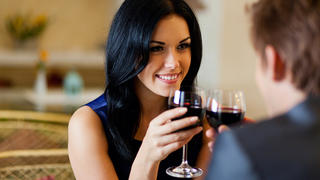 Young happy couple romantic date drink glass of red wine at restaurant, celebrating valentine day