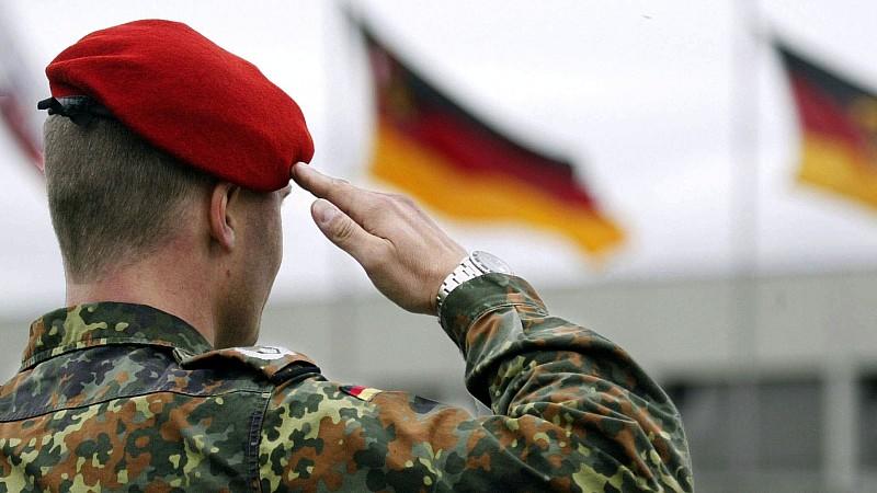 Ein Soldat der Bundeswehr salutiert, während vor ihm die deutsche Fahne weht (aufgenommen am 23.4.2004 in Speyer). Verteidigungsminister Struck (SPD) will gegen das Kölner Gerichtsurteil zur Einberufungspraxis der Bundeswehr Rechtsmittel einlegen. "I
