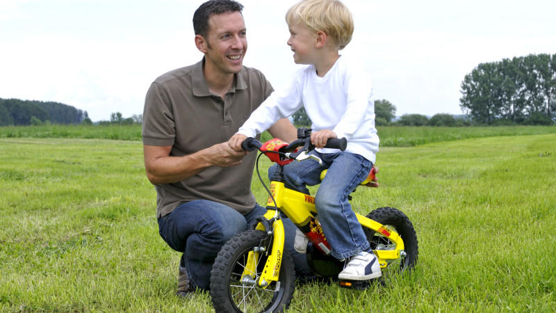 Vater unterstützt Sohn beim Fahrrad fahren lernen