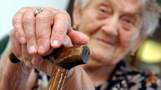 Im Caritas Seniorenzentrum "Albert Hirsch" stützt sich am 25.08.2003 die 90-jährige Elisabeth Schillert auf ihren Gehstock. Das 1996 erbaute Pflegeheim verfügt über 80 vollstationäre Plätze, 18 Tagespflegeplätze und 88 Unterkünfte für betreutes Wohnen. Am 28.08.2003 wird Sozialministerin Ulla Schmidt den Abschlussbericht der nach ihrem Vorsitzenden benannten Rürup-Kommission vorlegen. Dieser sieht neben einer beabsichtigten schrittweisen Anhebung des Renteneintrittalters von jetzt 65 auf 67 Jahre bis zum Jahr 2035 auch massive Leistungskürzungen vor. So soll die Rentenanpassung künftig an die Entwicklung der versicherungspflichtigen Entgelte gekoppelt werden. Vom Jahr 2010 an sollen Rentner zusätzlich zum Beitrag zur Pflegeversicherung einen von ihnen allein finanzierten Ausgleichsbeitrag von zwei Prozent des versicherungspflichtigen Einkommens zahlen. Das bedeutet für die Standardrente zusätzlich 20 Euro pro Monat. Foto: Patrick Pleul ZB FUNKREGIO OST/lbn - Honorarfrei nur für Bezieher des ZB-Regiodienstes -