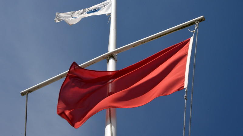 Die rote Flagge als Zeichen für das Badeverbot weht am 22.07.2014 am Ostseestrand von Timmendorfer Strand (Schleswig-Holstein). Wegen starker Strömung herrscht hier ein Badeverbot. Nach den tödlichen Badeunfällen an der Ostsee hat die Polizei an die 