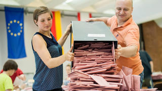 Wahlhelfer leeren am 25.05.2014 eine Wahlurne mit Briefwahlstimmen in der Mensa einer Schule in Berlin. Insgesamt sind rund 400 Millionen Wahlberechtigte in 28 EU-Ländern aufgerufen, über die Zusammensetzung des künftigen Europaparlaments zu entscheiden. Foto: Hauke-Christian Dittrich/dpa +++(c) dpa - Bildfunk+++
