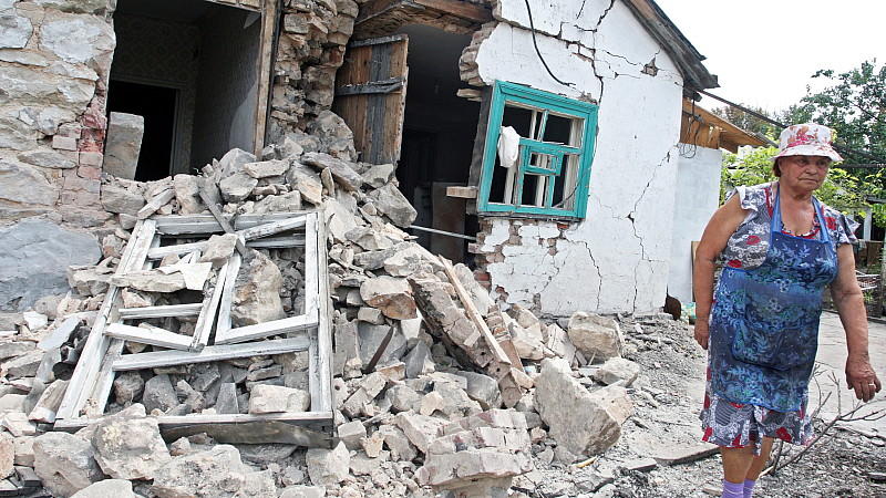 Eine Frau steht vor ihrem zerstörten Haus, 20 Kilometer entfernt von Donezk.