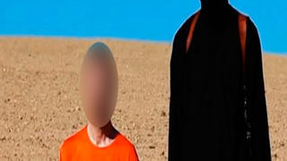HANDOUT - Screenshot eines Videos, das von der Terrormiliz Islamischer Staat (IS) am 14.09.2014 veröffentlicht wurde, zeigt den Angaben zufolge den britischen Entwicklungshelfer David Haines und einen IS-Kämpfer (r), der ein Messer in der Hand hält. Foto: EPA/ISLAMIC STATE VIDEO (ACHTUNG REDAKTIONEN: Das Gesicht wurde aus persönlichkeitsrechtlichen Gründen gepixelt. DPA nutzt das Bild von einer alternativen Quelle und kann keine Gewähr für den Wahrheitsgehalt und den genauen Ort geben - Nur zur redaktionellen Verwendung - Bestmögliche Qualität) +++(c) dpa - Bildfunk+++