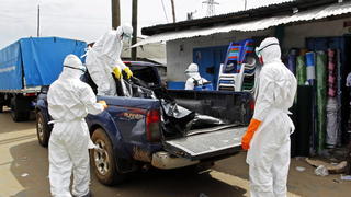epa04400484 A photograph made avaiable 14 September 2014 shows Liberian health care workers on an Ebola burial team collect the body of an Ebola victim in Westpoint, Monrovia, Liberia, 13 September 2014. The World Health Organization (WHO) has said the number of deaths from Ebola has risen to 2400 in West Africa with half that number coming from Liberia the hardest hit country in the region. EPA/AHMED JALLANZO +++(c) dpa - Bildfunk+++
