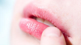 ILLUSTRATION -  Eine Frau befühlt mit einem Finger eine juckende und schmerzende Stelle auf ihrer Lippe. Foto: Franziska Gabbert