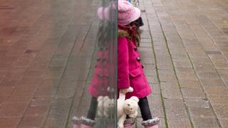 ARCHIV - Ein Mädchen steht am 21.01.2014 in Heilbronn (Baden-Württemberg) mit einem Teddybär an einer Haltestelle und spiegelt sich in einer Scheibe. Foto: Sebastian Kahnert/dpa (zu dpa "Pink, Ponys, Fleiß - Was ist wirklich «typisch Mädchen»?" vom 09.10.2014) +++(c) dpa - Bildfunk+++
