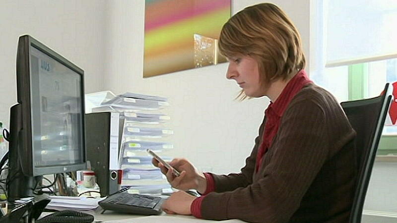 Frau bedient Smartphone am Arbeitsplatz