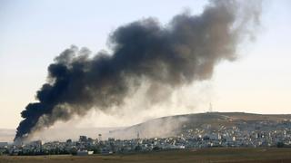 A Kurdish farmer drives a tractor on his field as thick black smoke rises over an eastern Kobani neighborhood following an airstrike November 8, 2014  Picture taken from the Turkish side of the Turkey-Syria border. REUTERS/Yannis Behrakis (SYRIA - Tags: MILITARY CONFLICT POLITICS)