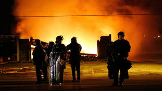 epa04502793 Police in riot stand in front of a burning building in Ferguson, Missouri, USA, 25 November 2014. According to St Louis County Prosecuting Attorney, the Grand jury decided that Ferguson police Officer Darren Wilson will not be charged in the shooting death of unarmed teenager Michael Brown. Protestors have taken to the streets angry that Ferguson police officer Darren Wilson was not indicted by a grand jury for the shooting death of teenager Michael Brown in August 2014. EPA/LARRY W. SMITH +++(c) dpa - Bildfunk+++