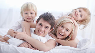 A happy family on white bed in the bedroom