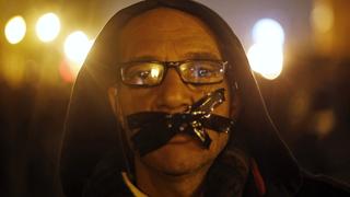 An anti-Mubarak protester stands with his mouth taped, during a protest against the government and military, after former Egyptian President Hosni Mubarak's verdict, around a statue of Egypt's former Army Chief of Staff Abdel Moneim Riad near Tahrir square in downtown Cairo November 29, 2014. Egyptian security forces fired tear gas and birdshot to disperse crowds protesting against a court's dropping of a case against Mubarak, according to a Reuters witness.The case against Mubarak was over the killing of protesters in the 2011 uprising that ended his 30-year rule.   REUTERS/Amr Abdallah Dalsh  (EGYPT - Tags: POLITICS CIVIL UNREST)