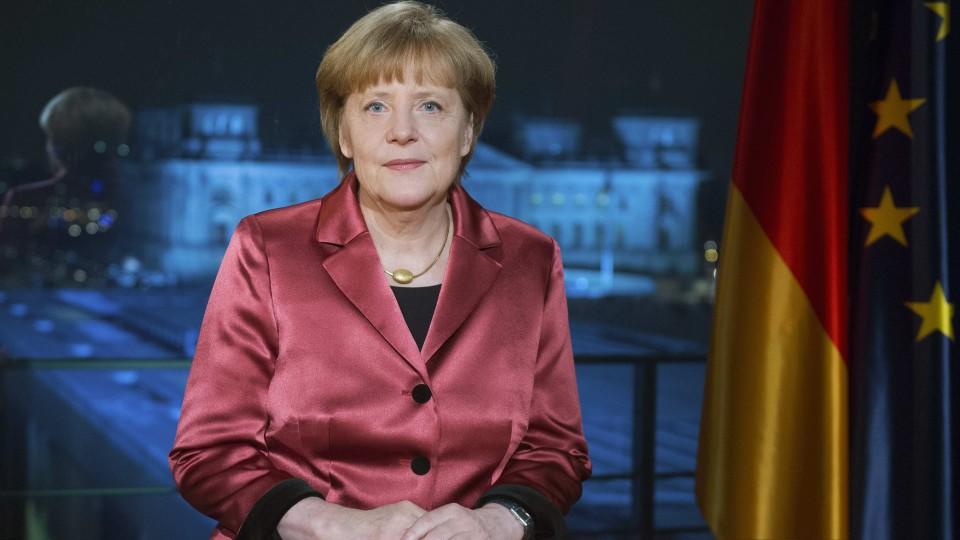 Bundeskanzlerin Angela Merkel sitzt vor der deutschen Flagge.