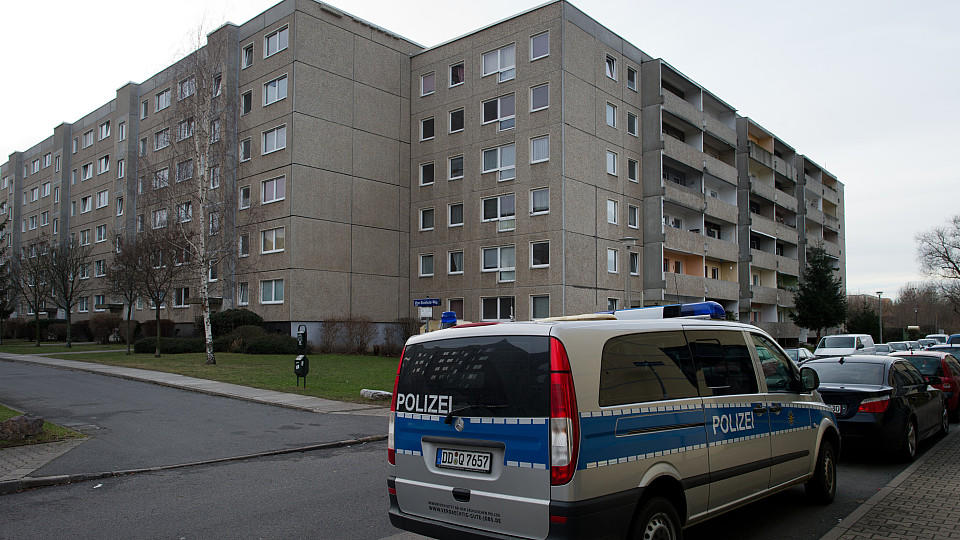 Ein Polizeiwagen vor einer Plattenbausiedlung.