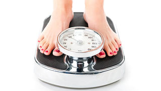Diet and weight, young woman standing on a scale, only feet to be seen