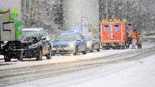 Einsatzkräfte der Polizei und Feuerwehr stehen am 24.01.2015 bei starkem Schneefall nach einem Unfall in Herne (Nordrhein-Westfalen) auf einer Straße. Eine Frau war mit ihrem Fahrzeug bei glatter Strasse in einen LKW gefahren. Am Morgen hat in Nordrhein-Westfalen starker Schneefall zu Verkehrsbehinderungen geführt.Foto: Marcel Kusch/dpa +++(c) dpa - Bildfunk+++