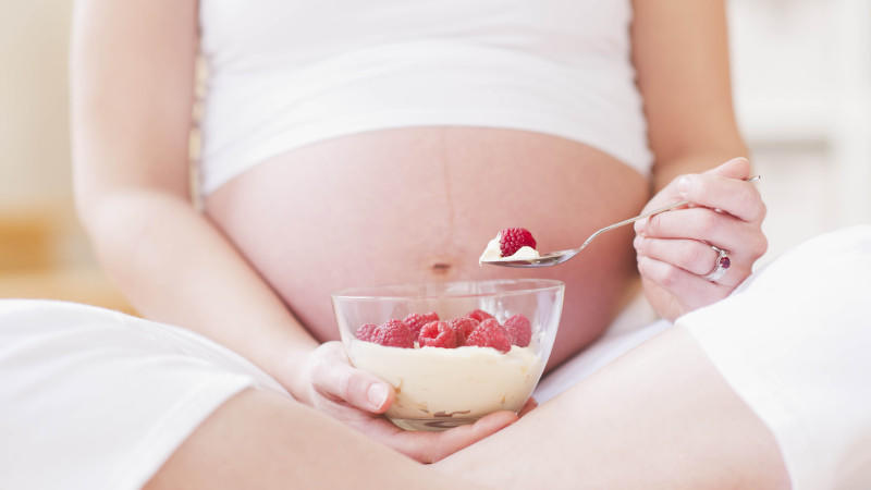 Eine schwangere Frau isst Himbeeren.