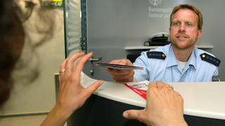Ein Beamter der Bundespolizei gibt 25.06.2008 einem Passagier im Düsseldorf International-Flughafen nach einer Ausweiskontrolle den Reisepass zurück. Foto: David Ebener dpa +++(c) dpa - Report+++