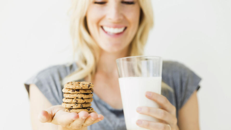 , Studio portrait of blonde woman holding glass of milk and cookies Keine Weitergabe an Drittverwerter.