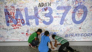 ARCHIV - Drei Kinder schreiben am 17.03.2014 in Sepang bei Kuala Lumpur, Malaysia, eine Nachricht auf eine Wand für die Passagiere des verschwundenen Flugzeuges aus Malaysia. Fast ein Jahr nach dem Verschwinden von Flug MH370 gehen Experten davon aus, das Wrack der Maschine aus Malaysia doch noch zu finden. Foto: Ahmad Yusni/epa (zu dpa "Experten zeigen sich bei MH370-Suche optimistisch" vom 03.03.2015) +++(c) dpa - Bildfunk+++