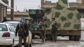 Fighters of the Kurdish People's Protection Units (YPG) walk past an armored vehicle along a street in the town of Tel Tamr February 25, 2015. Kurdish militia pressed an offensive against Islamic State in northeast Syria on Wednesday, cutting one of its supply lines from Iraq, as fears mounted for dozens of Christians abducted by the hardline group. The Assyrian Christians were taken from villages near the town of Tel Tamr, some 20 km (12 miles) to the northwest of the city of Hasaka. There has been no word on their fate. There have been conflicting reports on where the Christians had been taken. REUTERS/Rodi Said (SYRIA - Tags: POLITICS CIVIL UNREST CONFLICT)