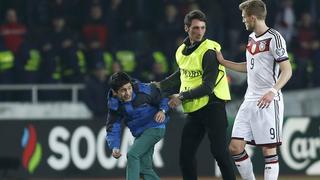 Germany's Andre Schuerrle (R) talks to security guard escorting a fan, who ran onto the pitch, during their Euro 2016 qualifier soccer match against Georgia in Tbilisi March 29, 2015. REUTERS/David Mdzinarishvili