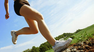 Beautiful woman runner in front of blue sky, low angle.
