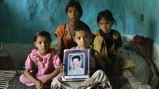 Yavatmal, INDIA:  (FILES) In this picture taken 18 April 2006, the four daughters of the late Indian cotton farmer Neelkhant Haste: Pranali (L), Seema (2L), Ruchali (3L), and Kajol (R) pose with his picture as they mourn his death at Yavatmal on the outskirts of Nagpur, after he committed suicide by consuming pesticide.   Farmer suicides in India's main cotton belt have reached their highest ever level with 216 dead since premier Manmohan Singh announced a major relief effort in July, community leaders said 04 September 2006.  The monthly death toll hit more than 100 for the first time in August and suicides are continuing at three a day among farmers hit hard by rising debt and falling cotton prices.Tallies compiled by activists show 767 farmers killed themselves in the last 12 months in the Vidarbha region in western Maharashtra state, with many setting themselves alight or drinking pesticide. Activists say only a few hundred farmers have been helped by Singh's 37.5-billion rupee (835 million USD) relief package announced after a two-day visit to Vidarbha.   AFP PHOTO/Sebastian D'SOUZA/FILES  (Photo credit should read SEBASTIAN D'SOUZA/AFP/Getty Images)
