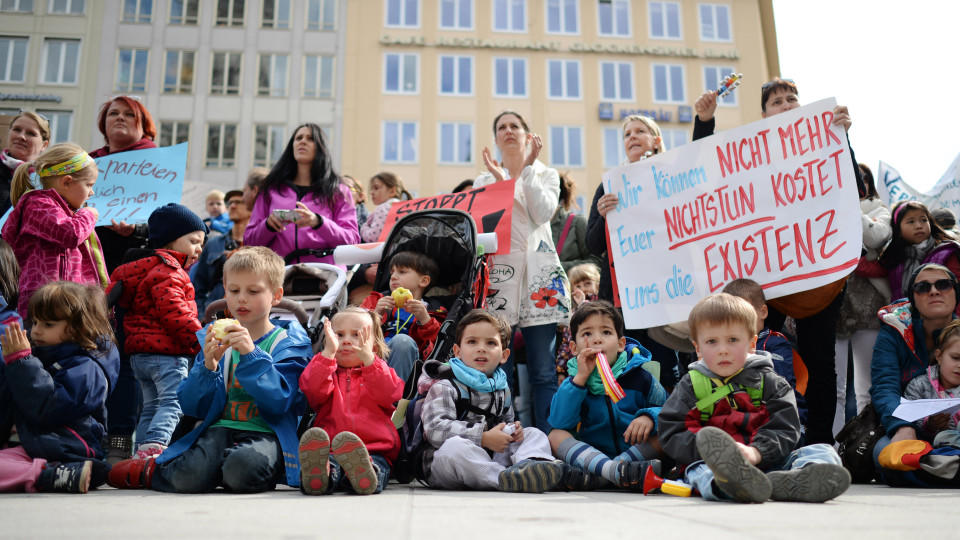 Zahlreiche Eltern und Kinder nehmen am 27.05.2015 an einer Kundgebung auf dem Marienplatz in München (Bayern) teil; zwei Teilnehmerinnen halten ein Plakat mit der Aufschrift «Wir können nicht mehr. Euer Nichtstun kostet uns die Existenz» in Händen. Beschäftigte kommunaler Kitas befinden sich seit drei Wochen im Streik. Eltern rufen zu weiteren Verhandlungen zwischen Erziehern und Kita-Betreibern im Kita-Streik auf. Foto: Andreas Gebert/dpa +++(c) dpa - Bildfunk+++