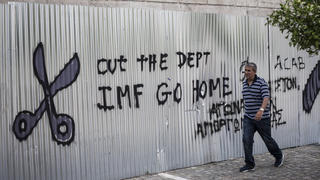 dpatopbilder - A man walks in front of a graffiti reading "cut the dept, IMF go home" outside the university of Athens,  Greece, 26 June 2015. Photo: Socrates Baltagiannis/dpa (zu dpa "Stimmen aus Griechenland - Studenten kommentieren die Krise" am 27.06.2015) +++(c) dpa - Bildfunk+++