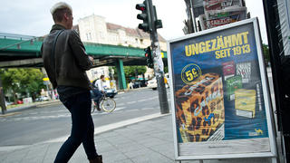 ARCHIV - Eine Frau läuft am 28.06.2014 in Berlin an einem Kiosk neben einem Aufsteller mit Zigarettenwerbung vorbei. Foto: Daniel Naupold/dpa (zu dpa "Minister Schmidt will Tabak-Werbung komplett verbieten" vom 27.06.2015) +++(c) dpa - Bildfunk+++