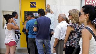 People line up to withdraw cash from an automated teller machine (ATM) outside a Piraeus Bank branch in Iraklio on the island of Crete, Greece June 28, 2015. Greece said it may impose capital controls and keep its banks shut on Monday after creditors refused to extend the country's bailout and savers queued to withdraw cash, taking Athens' standoff with the European Union and the International Monetary Fund to a dangerous new level.  REUTERS/Stefanos Rapanis