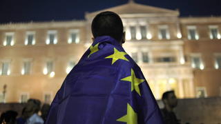 epaselect epa04839580 A demonstrator is covered with a European Union flag during a pro euro rally in front of the Greek Parliament in Athens Greece, 09 July 2015. Eurogroup President Jeroen Dijsselbloem on 08 July referred Greece's official request for financial assistance from the European Stability Mechanism (ESM) to the European Central Bank (ECB) and the European Commission. In a letter addressed to European Commissioner for Economic and Monetary Affairs Pierre Moscovici and ECB President Mario Draghi, Dijsselbloem informs them of Greece's request for 'stability support in the form of a loan' and asks them to assess the request under ESM rules. EPA/FOTIS PLEGAS G. +++(c) dpa - Bildfunk+++